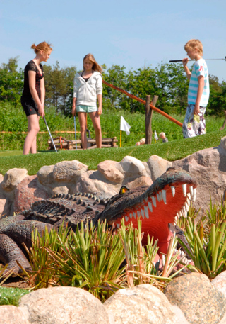 Krokodil framför barn som spelar golf