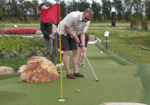 Man aiming for the cup while playing adventure golf