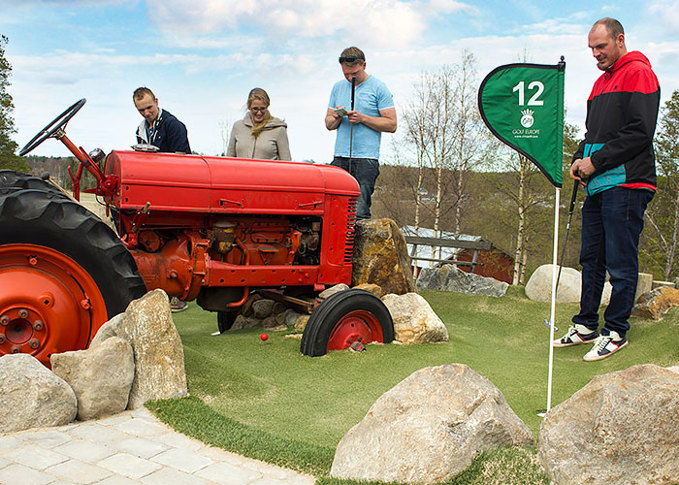 En golfboll spelas under en traktor som utgör ett hinder på Lufta Campings äventyrsgolf